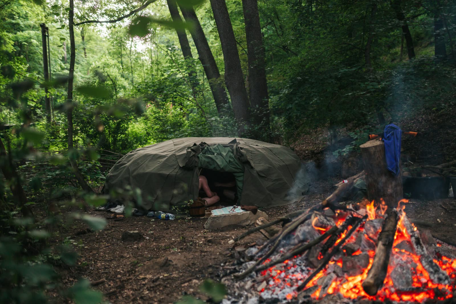 A sweat lodge in the forest and a fire with glowing stones